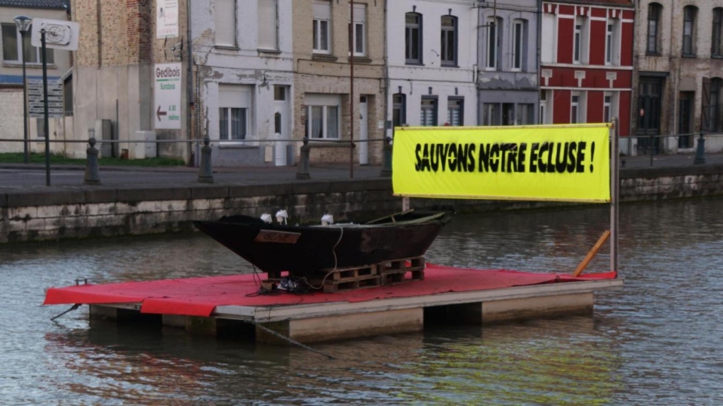 « Sauvons notre écluse ! » En lettres noires sur fond jaune, c’est le message qu’affiche, directement sur le canal, le collectif pour la sauvegarde du canal du Haut-Pont. (Photo extraite du site lavoixdunord.fr))