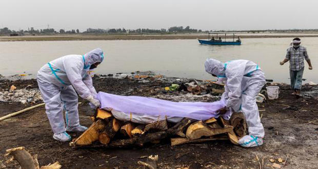 Des hommes placent un tissu blanc sur le corps d'un proche décédé du COVID-19 avant sa crémation sur les rives du Gange à Garhmukteshwar, dans l'État septentrional de l'Uttar Pradesh, en Inde, le 6 mai. (Photo D.R.)